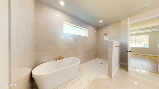 bathroom featuring separate shower and tub, wood-type flooring, and tile walls