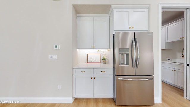 kitchen featuring stainless steel refrigerator with ice dispenser, light hardwood / wood-style floors, and white cabinetry