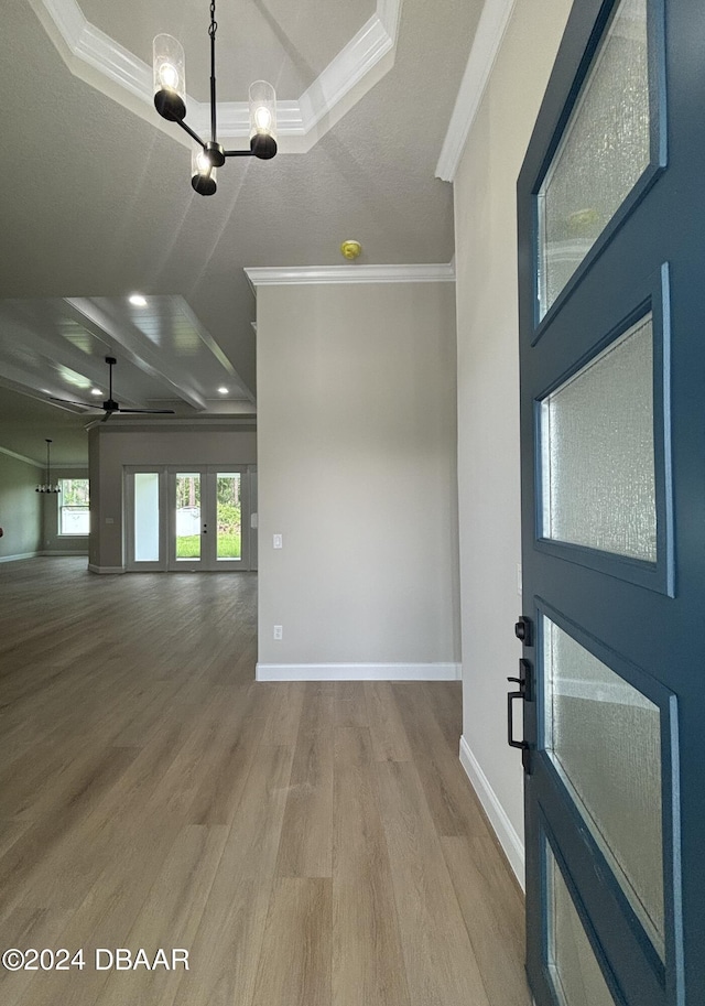 interior space with hardwood / wood-style flooring, ceiling fan with notable chandelier, a raised ceiling, and crown molding