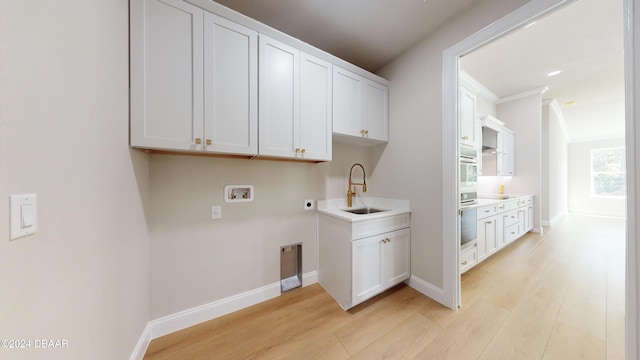 clothes washing area featuring sink, cabinets, washer hookup, hookup for an electric dryer, and light hardwood / wood-style flooring