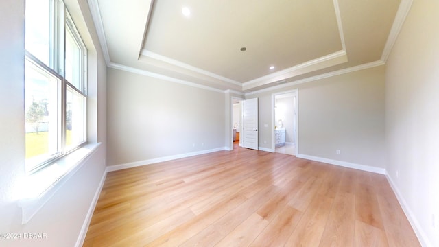 spare room with light hardwood / wood-style floors, a raised ceiling, and ornamental molding