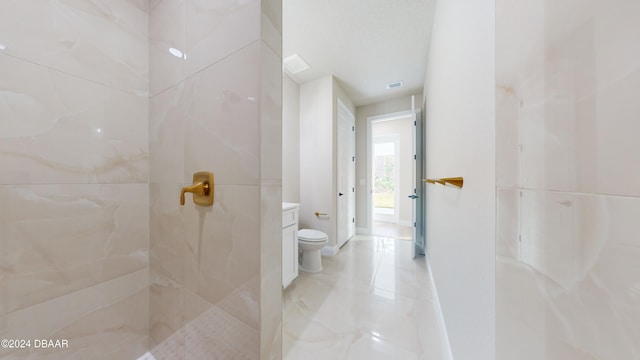 bathroom with a tile shower and toilet