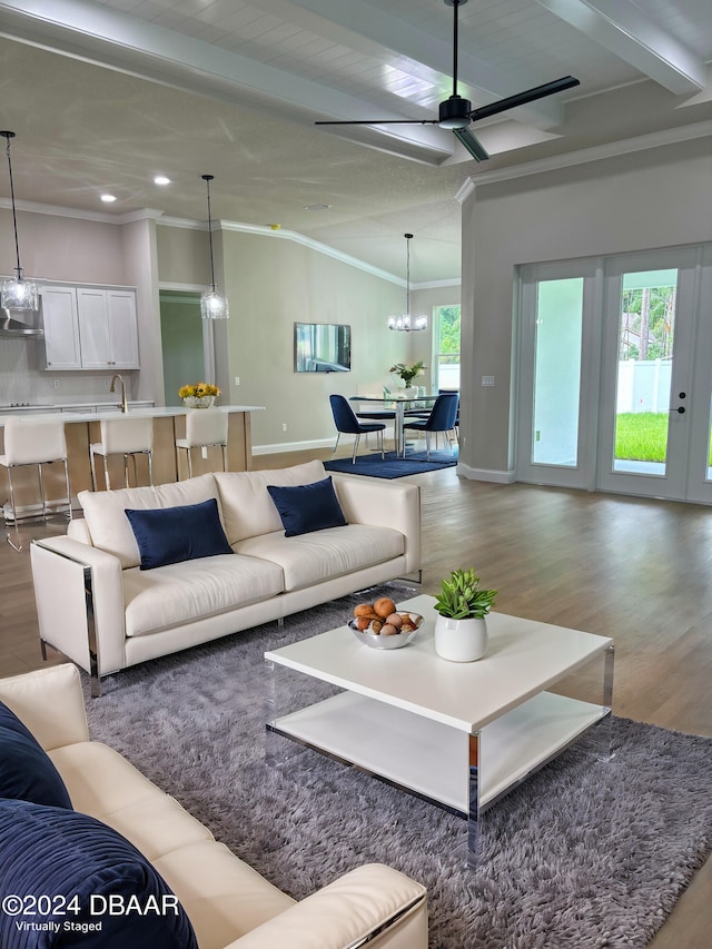 living room featuring sink, crown molding, vaulted ceiling, ceiling fan with notable chandelier, and light wood-type flooring