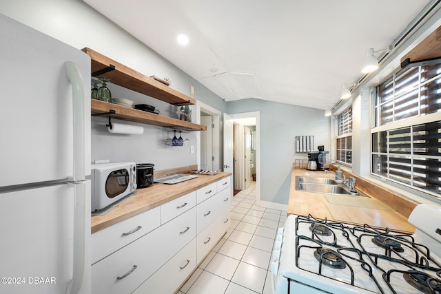 kitchen with wood counters, white appliances, sink, white cabinets, and light tile patterned flooring