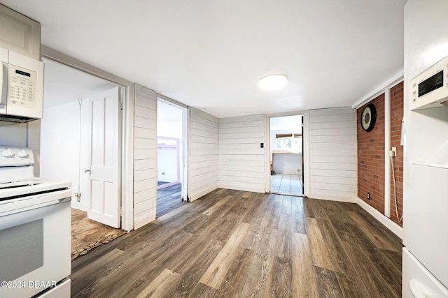 unfurnished living room featuring wooden walls and dark wood-type flooring