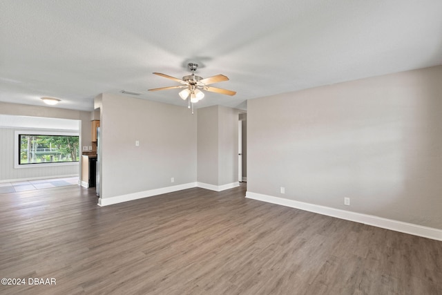 unfurnished room with a textured ceiling, ceiling fan, and dark wood-type flooring