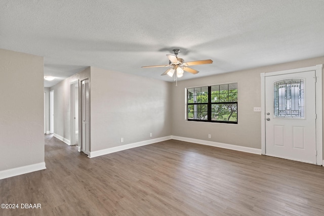 interior space with a textured ceiling, ceiling fan, and dark wood-type flooring