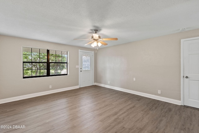 empty room featuring a textured ceiling, ceiling fan, and dark wood-type flooring