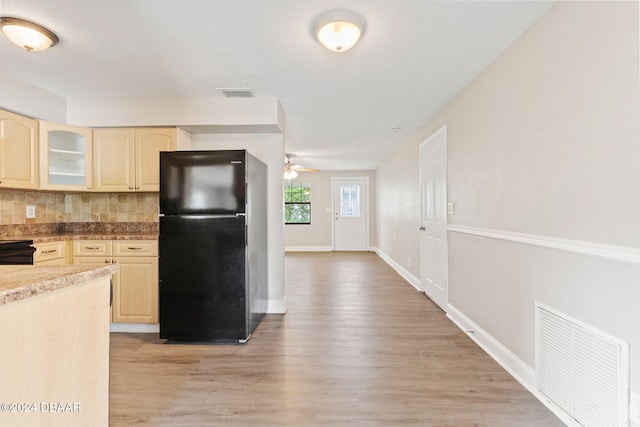 kitchen with backsplash, light hardwood / wood-style flooring, black appliances, and light brown cabinets