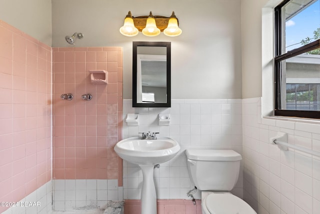 bathroom with toilet, tile walls, and sink