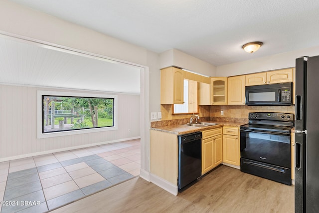 kitchen featuring black appliances, sink, light wood-type flooring, light brown cabinetry, and tasteful backsplash