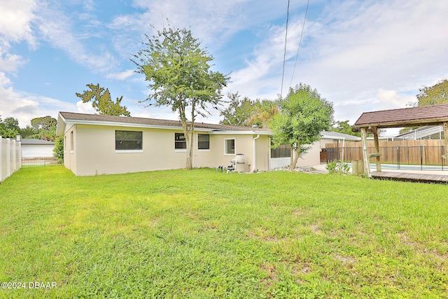 rear view of property featuring a yard and a pool