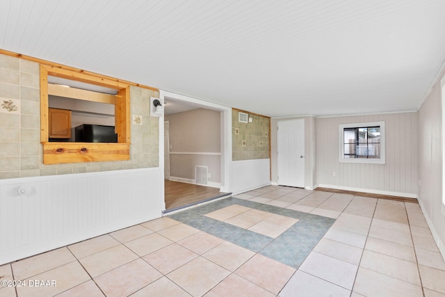 empty room with light tile patterned floors and crown molding