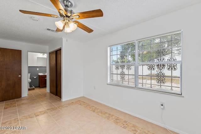 tiled empty room with ceiling fan and a textured ceiling