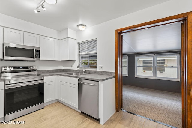 kitchen with white cabinets, light hardwood / wood-style floors, sink, and stainless steel appliances