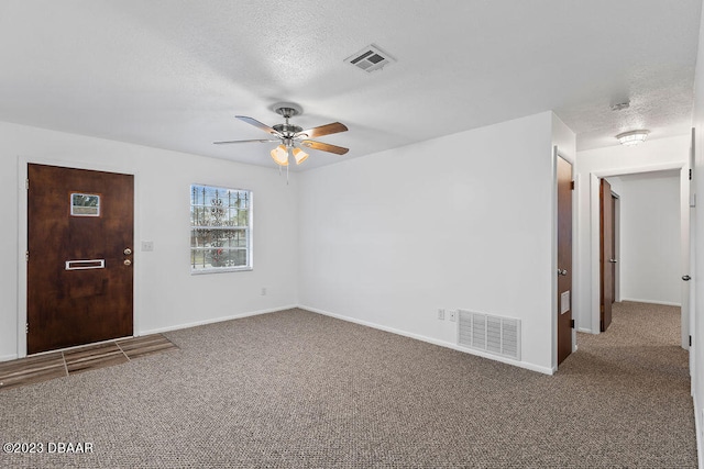 carpeted spare room featuring ceiling fan and a textured ceiling