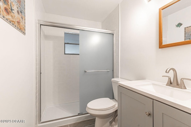 bathroom with vanity, a shower with shower door, and toilet