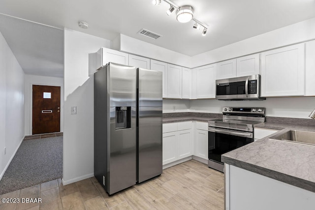 kitchen with light carpet, appliances with stainless steel finishes, white cabinetry, and sink