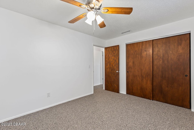 unfurnished bedroom featuring carpet flooring, ceiling fan, a textured ceiling, and a closet