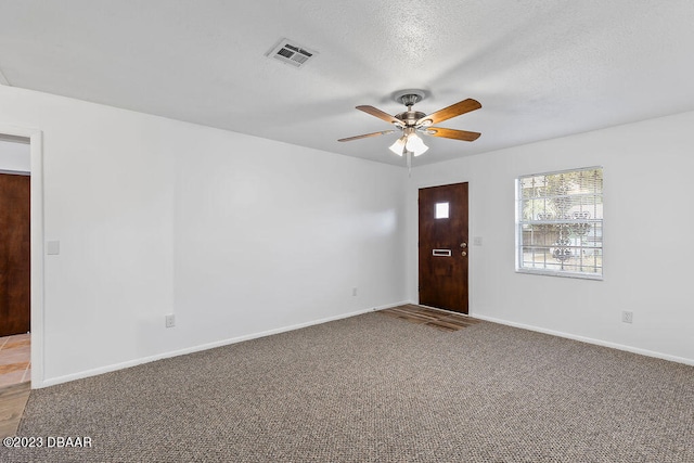 spare room with a textured ceiling, carpet floors, and ceiling fan