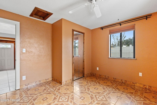 unfurnished room featuring a ceiling fan, a textured wall, and light tile patterned floors