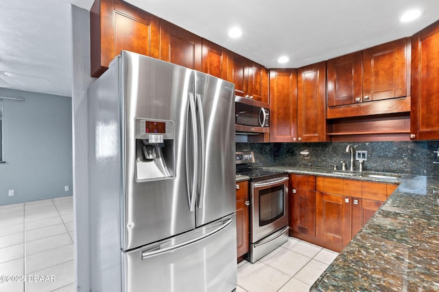 kitchen with light tile patterned floors, appliances with stainless steel finishes, a sink, and tasteful backsplash