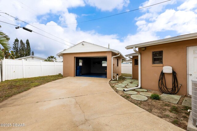 detached garage featuring concrete driveway and fence