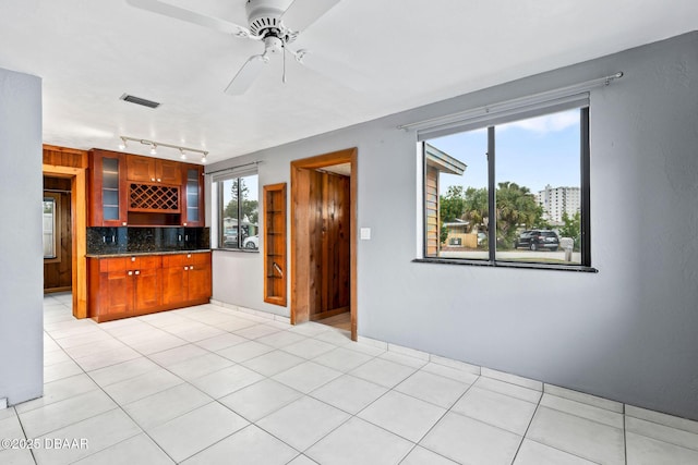 kitchen featuring glass insert cabinets, light tile patterned floors, tasteful backsplash, and visible vents