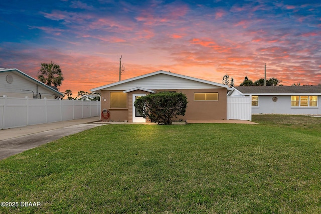 view of front of property with stucco siding, fence, and a lawn