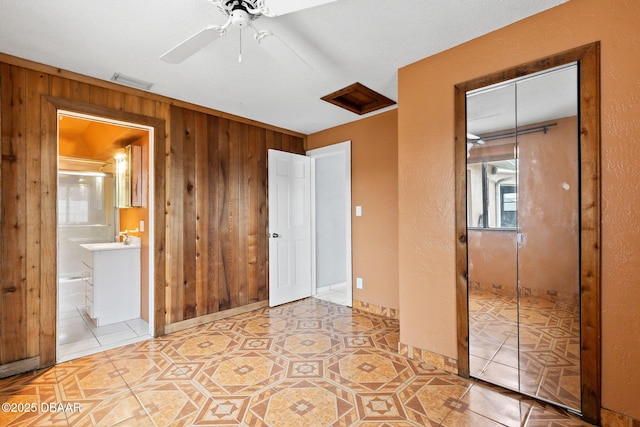 unfurnished bedroom with a closet, visible vents, wooden walls, and light tile patterned floors