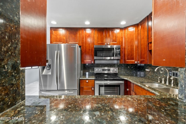 kitchen featuring recessed lighting, stainless steel appliances, a sink, backsplash, and dark stone countertops