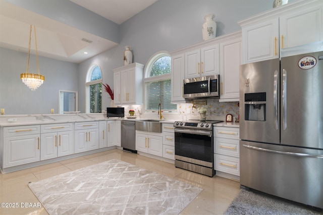 kitchen with decorative backsplash, appliances with stainless steel finishes, white cabinetry, a sink, and light tile patterned flooring