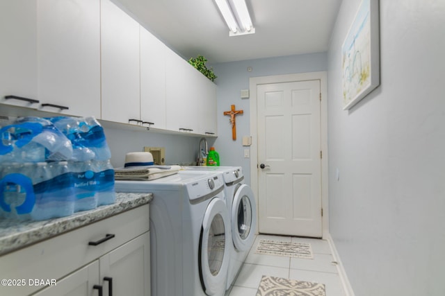 clothes washing area featuring light tile patterned floors, baseboards, cabinet space, and washer and clothes dryer