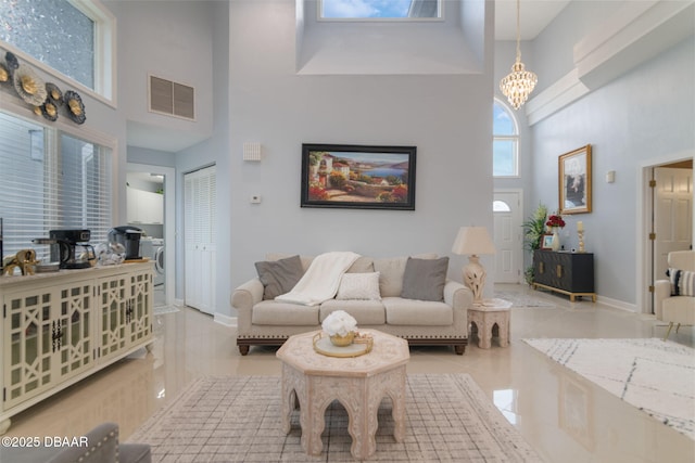 living area with visible vents, a towering ceiling, tile patterned floors, and an inviting chandelier