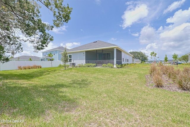 back of property with central AC unit, a sunroom, and a lawn