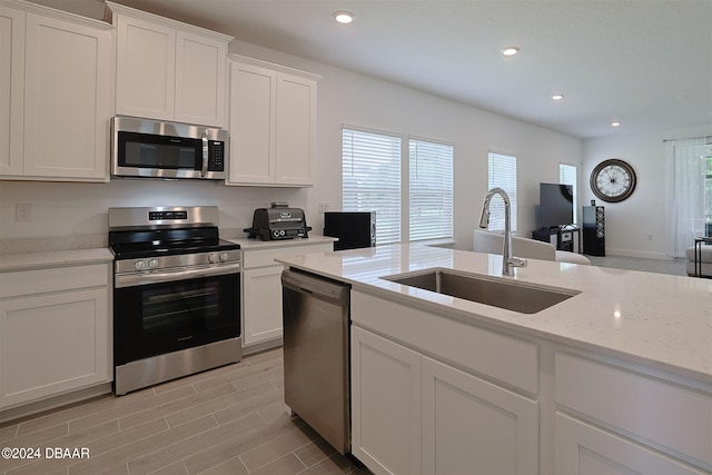 kitchen with a wealth of natural light, white cabinetry, sink, and appliances with stainless steel finishes