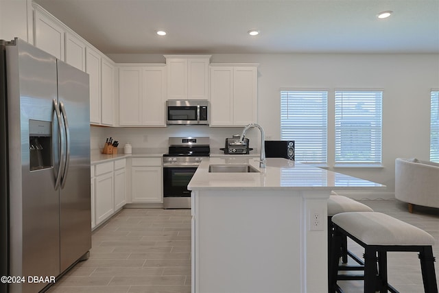 kitchen featuring appliances with stainless steel finishes, sink, a breakfast bar, white cabinets, and a center island