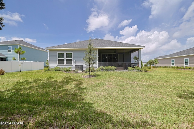 rear view of house featuring a sunroom and a yard