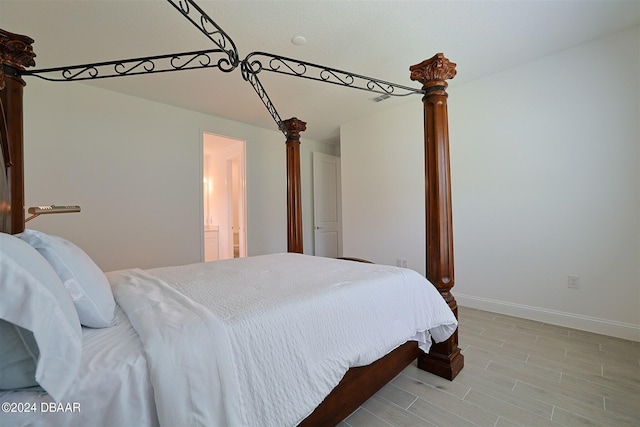 bedroom featuring ornate columns, light hardwood / wood-style flooring, and connected bathroom