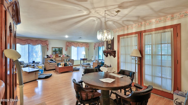 dining area with light hardwood / wood-style floors and a notable chandelier