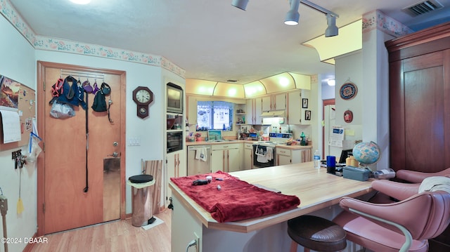 kitchen featuring a kitchen bar, dishwasher, sink, electric range, and light wood-type flooring