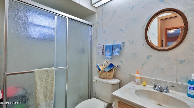 bathroom with a shower with shower door, vanity, and toilet