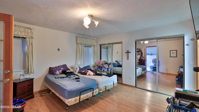 bedroom featuring multiple closets and light hardwood / wood-style flooring