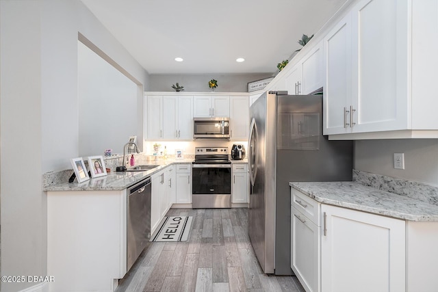 3417 Medici Blvd, New Smyrna Beach, FL 32168 - kitchen featuring stainless steel appliances, light wood-style flooring, white cabinetry, recessed lighting, and light stone counters
