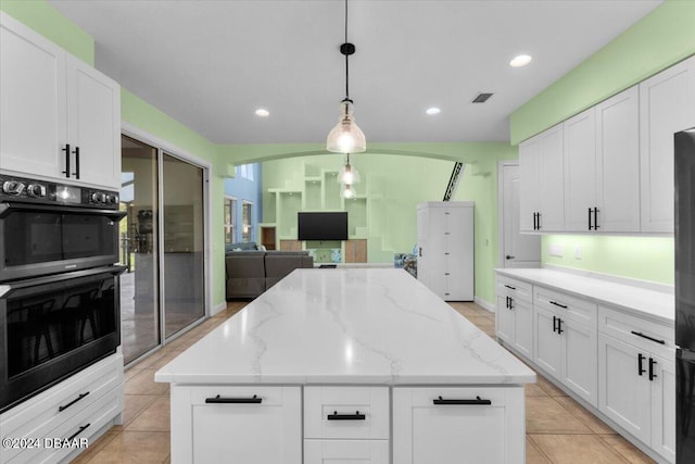 kitchen with white cabinets, hanging light fixtures, a center island, and double oven