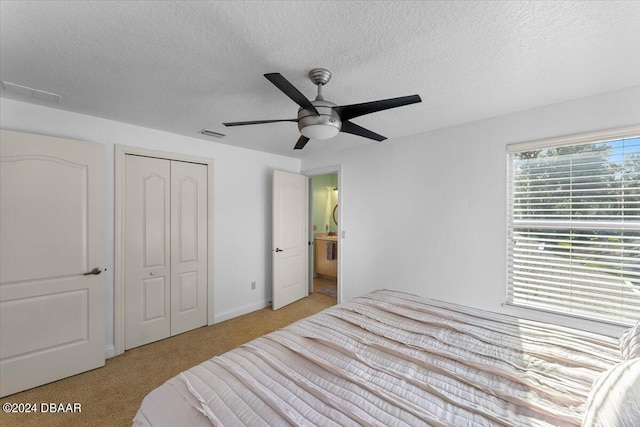 carpeted bedroom with a textured ceiling, ceiling fan, and a closet