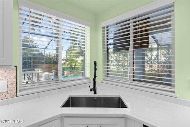 kitchen with white cabinetry, sink, light stone countertops, and plenty of natural light