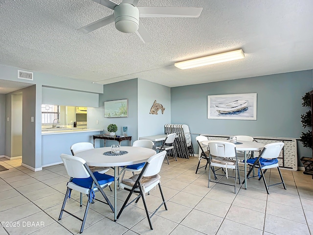 tiled dining space featuring a textured ceiling and ceiling fan