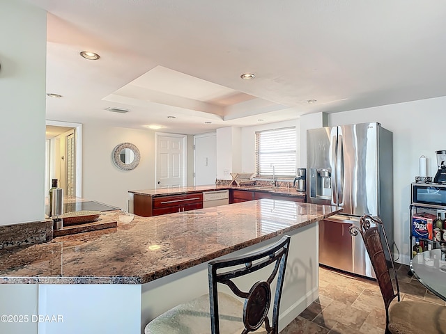 kitchen with stainless steel fridge with ice dispenser, a kitchen breakfast bar, white dishwasher, kitchen peninsula, and a raised ceiling