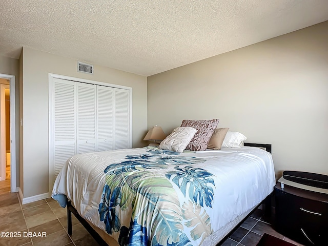 bedroom with dark tile patterned flooring, a closet, and a textured ceiling